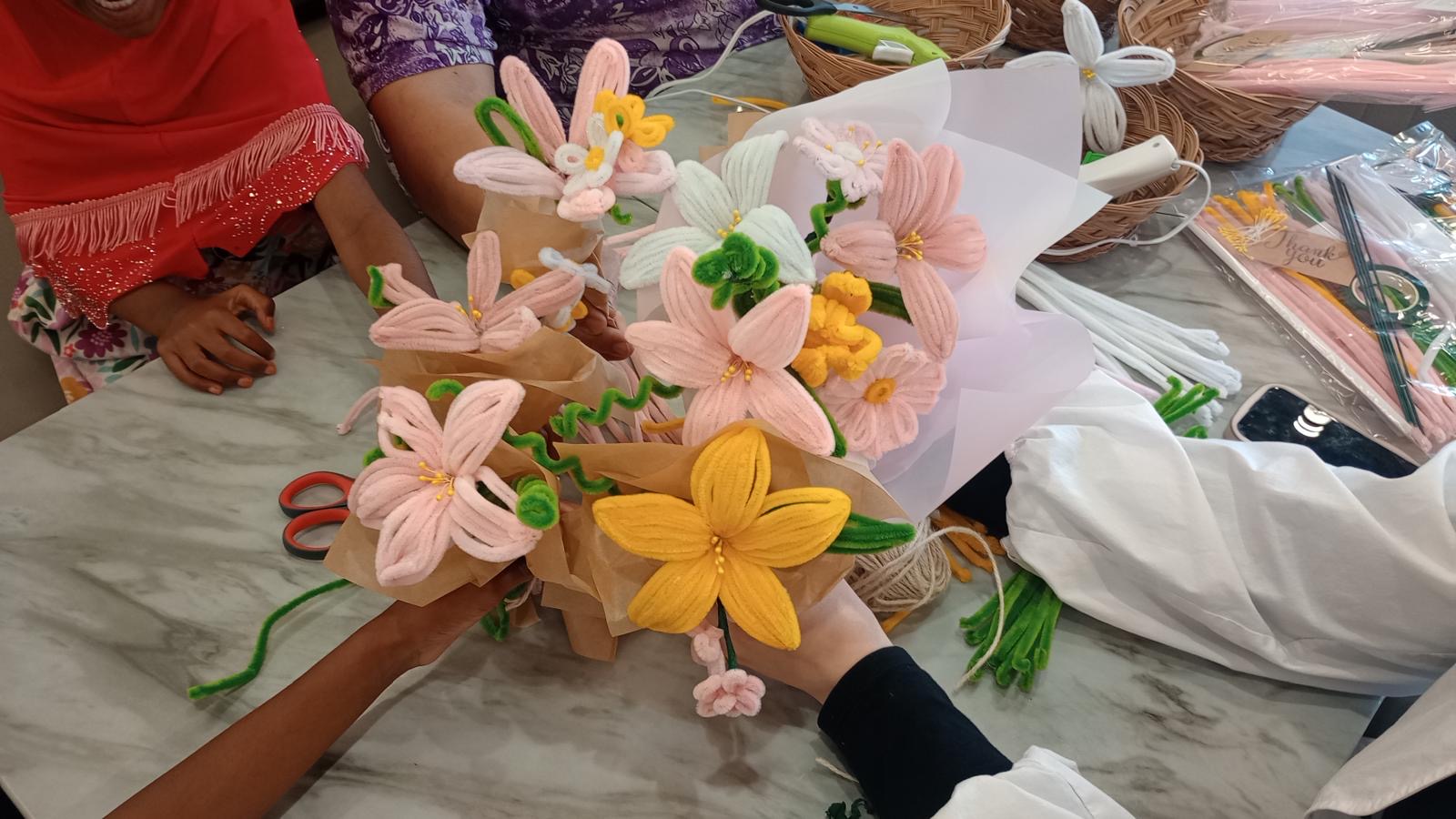 Handmade pink, white and yellow chenille-stem lily bouquets held over a marble table